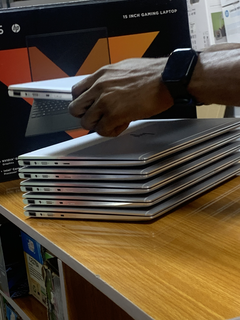 Stacked Neat UK Used Laptops placed beside a Victus gaming laptop