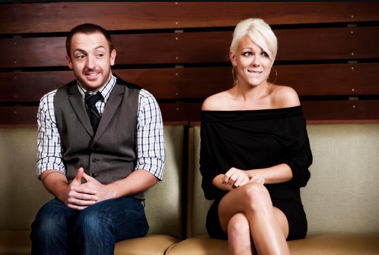 Man and woman sitting across each other in an awkward moment - prank hotline numbers to call