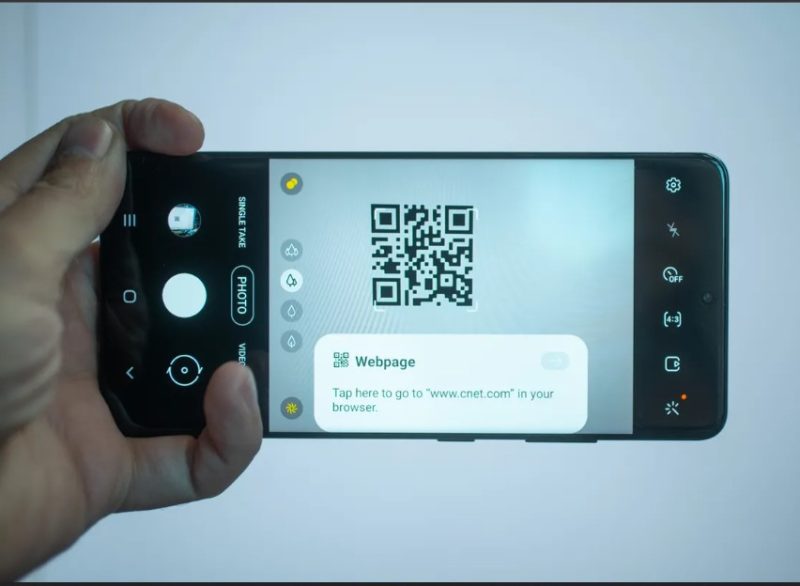 A hand scanning a qr code with the camera app using an Android phone